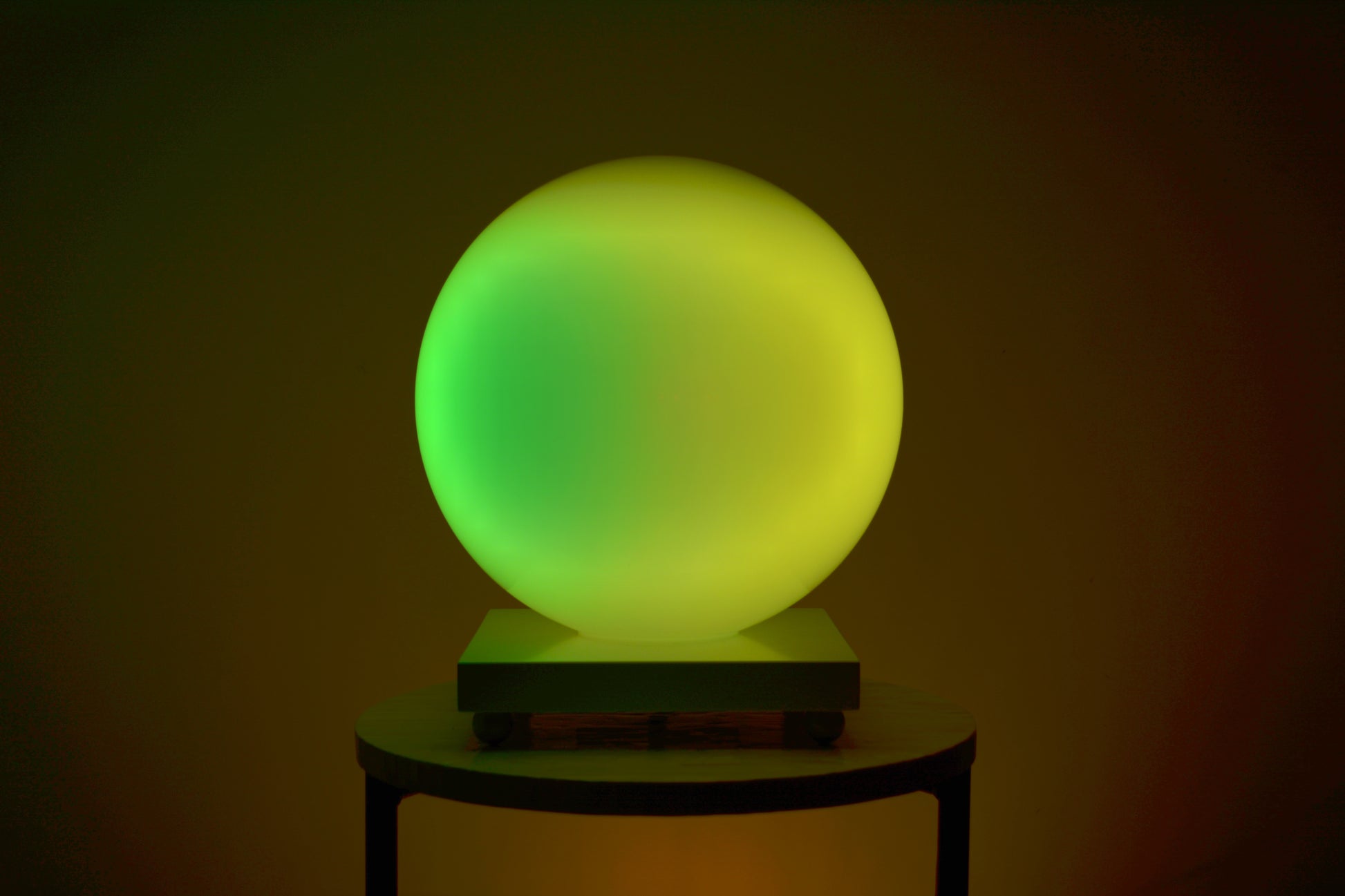 Une Sensosphère ayant un dégradé de couleur jaune et vert est posée sur une table basse